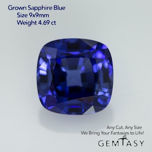May include: A deep blue sapphire gemstone, cut in a cushion shape. It measures 9mm x 9mm and weighs 4.69 carats. The gemstone is on a white background. Grown Sapphire Blue. Size 9x9mm. Weight 4.69 ct. Any Cut, Any Size. We Bring Your Fantasies to Life! GEMTASY