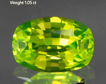 May include: A vibrant, lime-green Lutetium Aluminum Garnet gemstone. The gem is oval-shaped, with a size of 6x4mm and a weight of 1.05 ct. The image also includes the Gemtasy logo.
