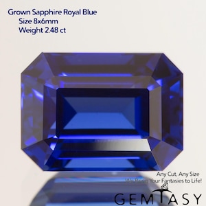 May include: A faceted, royal blue sapphire gemstone with an emerald cut. The gem is 8x6mm and weighs 2.48 carats. Text on the image reads "Grown Sapphire Royal Blue" and "Any Cut, Any Size". The gem is displayed on a white background.