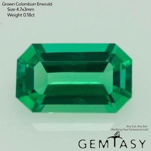 May include: A vibrant, rectangular-cut, grown Colombian emerald. The gemstone is a deep, rich green color with a faceted surface. The size is 4.7x3mm and weighs 0.18ct. The image also includes the text "GEMTASY".