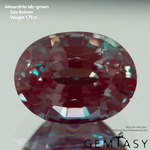 May include: An oval, lab-grown alexandrite gemstone. The gem is a deep burgundy color with flashes of teal and measures 8x6mm. The weight is 1.79 ct. The image includes the text "Alexandrite lab-grown, Size 8x6mm, Weight 1.79 ct."