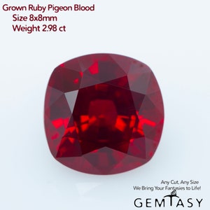 Può includere: Un rubino rosso intenso taglio a cuscino, di circa 8 mm x 8 mm. L'immagine include il testo "Grown Ruby Pigeon Blood, Size 8x8mm, Weight 2.98 ct." La gemma è di un colore rosso intenso ed è mostrata su sfondo bianco. È presente anche il testo "Any Cut, Any Size We Bring Your Fantasies to Life!"