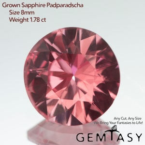 May include: A round, pink, 8mm grown sapphire padparadscha gemstone weighing 1.78 carats. The gemstone has a faceted cut and is set against a white background.
