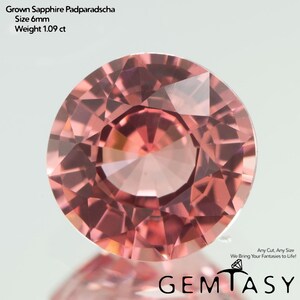 Può includere: Una gemma di zaffiro Padparadscha rosa-arancio, rotonda e sfaccettata. La gemma misura 6 mm e pesa 1,09 ct. L'immagine include il testo "Grown Sapphire Padparadscha", "Size 6mm" e "Weight 1.09 ct". È visibile anche il logo "GEMTASY".