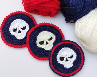 May include: Three crocheted skull-shaped coasters with a navy blue background and a red border. The coasters are made with white yarn and have a skull design in the center.