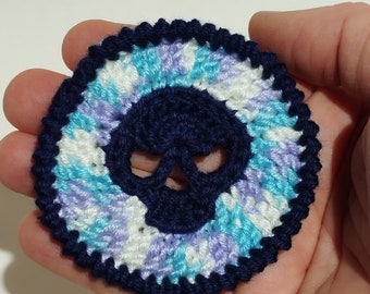 May include: A crocheted skull design with a blue skull and a white, blue, and purple background.