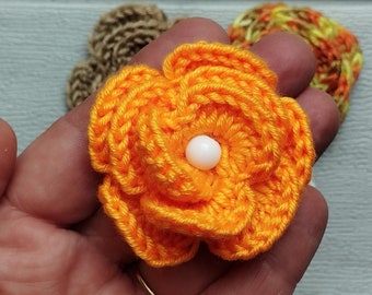 May include: A crocheted orange flower with a white pearl button in the center.
