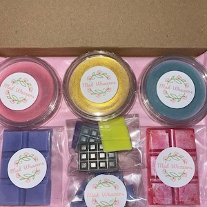 May include: A box of wax melts with different scents and colors. The wax melts are packaged in clear containers and plastic bags. The wax melts are labeled with the text "Mad Waxxers".