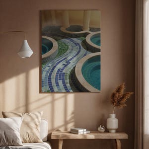 Puede incluir: Una obra de arte enmarcada que representa una serie de piscinas circulares con agua turquesa. Las piscinas están rodeadas de piedra beige y conectadas por un camino de mosaico de baldosas azules y verdes. La obra está colgada en una pared marrón.
