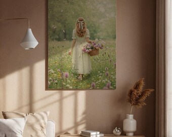 May include: A framed print showing a person in a light dress walking through a wildflower meadow, carrying a basket of pink and purple flowers. The scene is set in a meadow with soft light and a blurred background.