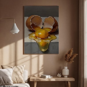 Könnte beinhalten: Ölgemälde, das ein zerbrochenes Ei mit herausfließendem Eigelb darstellt. Die Eierschale ist braun und das Eigelb leuchtend gelb. Der Hintergrund ist ein neutrales Grau und Weiß. Das Gemälde wird an einer Wand in einem Raum mit neutralen Tönen ausgestellt.