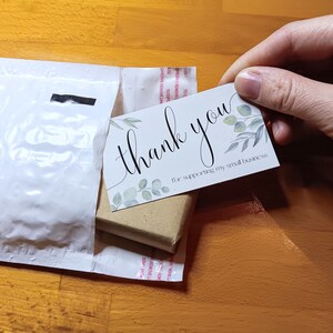 May include: A white thank you card with green leaves and the text "thank you for supporting my small business".