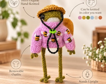 May include: A hand-knitted frog doll wearing a pink sweater with a bee pattern, a yellow hat, and a black drawstring cord. The frog has long green legs, black eyes, and a white chin. Text includes 100% Organic Hand-Knitted, Can be knitted in color you want, Removable Outfits, and Stands Upright.