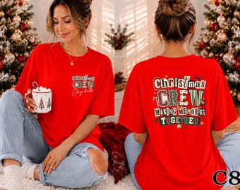 May include: A bright red short-sleeved t-shirt featuring a graphic print. The front displays the text Christmas CREW and a name. The back features the text Christmas CREW MAKING MEMORIES TOGETHER in a multi-colored, patterned font style.