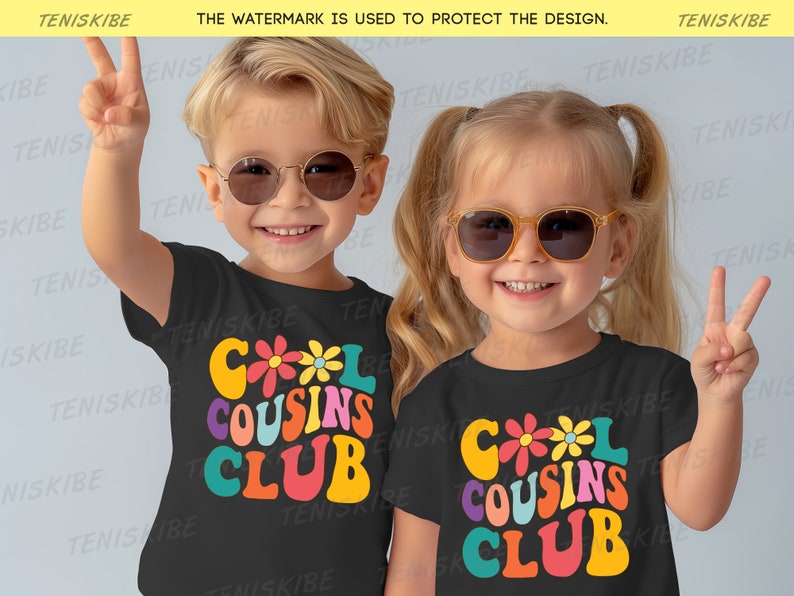 K&ouml;nnte beinhalten: Zwei Kinder tragen schwarze T-Shirts mit einem bunten "Cool Cousins Club"-Motiv. Die Kinder tragen Sonnenbrillen und l&auml;cheln.