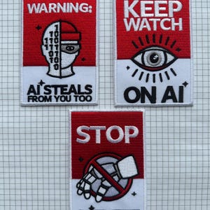 Puede incluir: Tres parches rectangulares con diseños rojos y blancos. El parche superior dice "WARNING:" con un gráfico de una cara y el texto "AI STEALS FROM YOU TOO." El parche del medio dice "KEEP WATCH ON AI" con un gráfico de ojo. El parche inferior dice "STOP AI THEFT."