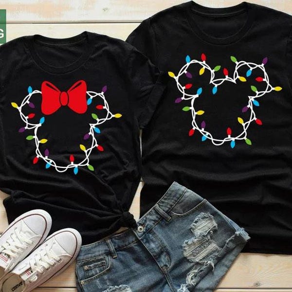 Könnte beinhalten: Zwei schwarze T-Shirts mit einem Mickey Mouse-Kopf-Design aus Weihnachtsbeleuchtung. Ein Shirt hat eine rote Schleife. Weiße Turnschuhe und Jeansshorts sind im Vordergrund. Ideal für Paare oder Partner-Outfits.