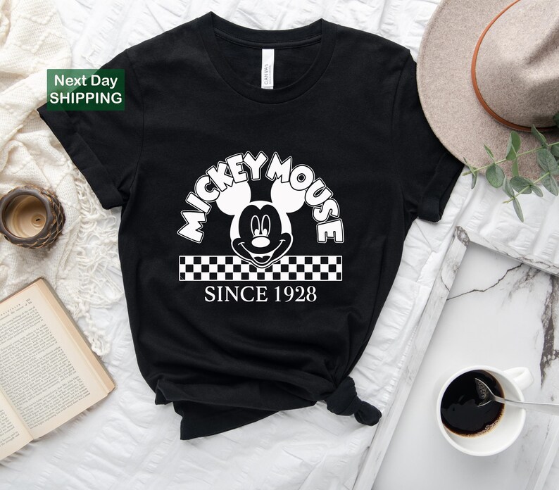a mickey mouse since shirt sitting on top of a bed