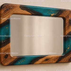 Op de afbeelding: Rechthoekige spiegel met een houten frame en een turquoise epoxyharsinleg. Het frame heeft afgeronde hoeken en een natuurlijk houtnerfpatroon. Gouden spikkels zijn ingebed in de hars. Een decoratief item voor in huis.