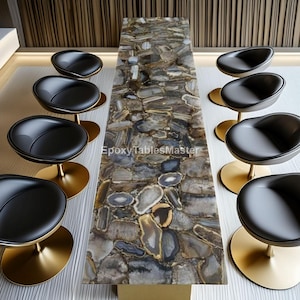 May include: A contemporary dining table with a stone-effect surface and black leather chairs with gold-coloured bases. The table is rectangular and the chairs are arranged around it. The room has a modern design.