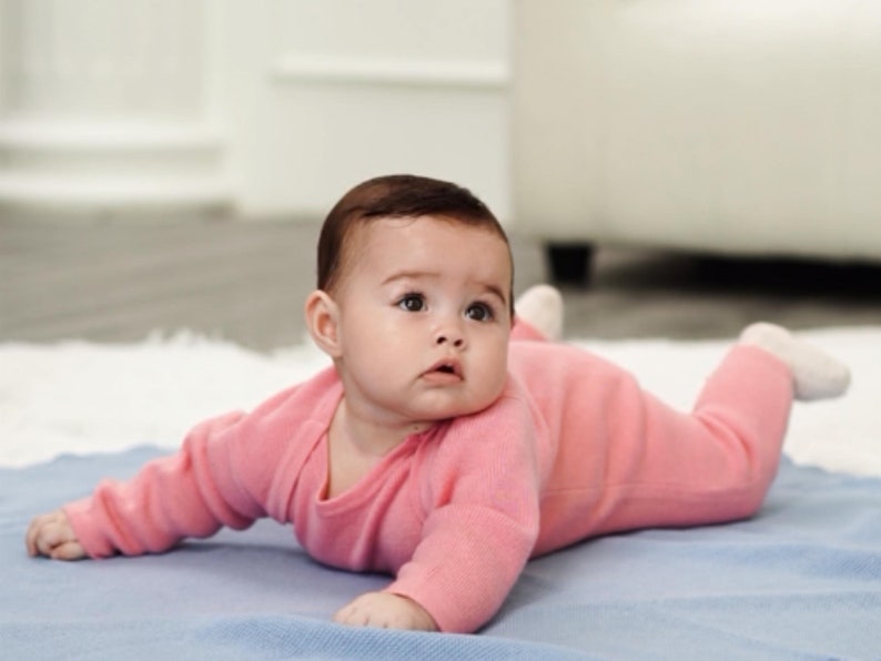 Baby in rosa Merino-Strampler von der Seite