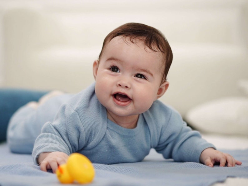 Baby in Merino-Strampler blau lacht