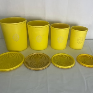 Puede incluir: Un juego de cuatro recipientes de plástico amarillo con tapas a juego. Los recipientes son cilíndricos con un diseño floral. Las tapas son redondas con un patrón acanalado. Los recipientes son de diferentes tamaños.