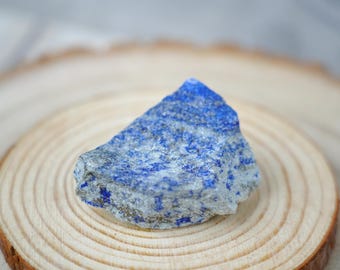 Puede incluir: Un cristal de lapislázuli áspero, azul y blanco sobre una superficie de madera.
