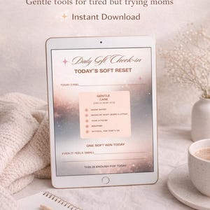 Könnte beinhalten: Ein digitales Tablet zeigt ein "Daily Soft Check-in" Formular mit Aufforderungen zur Selbstpflege. Der Text lautet "75 Soft Mom Reset" und "Gentle tools for tired but trying moms". Ein Notizblock, ein Stift und eine Kaffeetasse sind ebenfalls im Bild.
