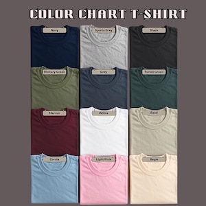 May include: A color chart of T-shirts in various colors, including navy, sports grey, black, military green, grey, forest green, maroon, white, sand, corola, light pink, and begie. Each shirt is neatly folded and labeled with its color.