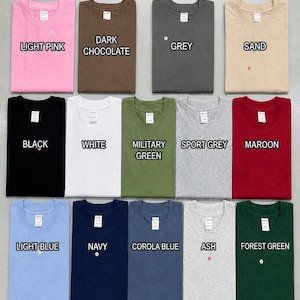 May include: A T-shirt color chart displaying fourteen folded crew neck shirts in various colors including light pink, dark chocolate, grey, sand, black, white, military green, sport grey, maroon, light blue, navy, corola blue, ash, and forest green.