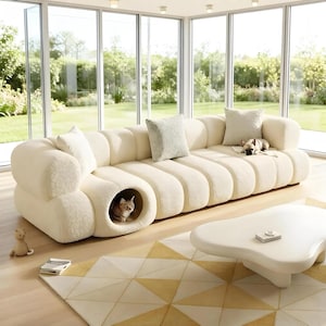 May include: A cream-colored, modern sectional sofa with a built-in cat bed. The sofa has a rounded, ribbed design and includes several throw pillows. A small dog and a cat are on the sofa. A white coffee table and a geometric rug are in front of the sofa.
