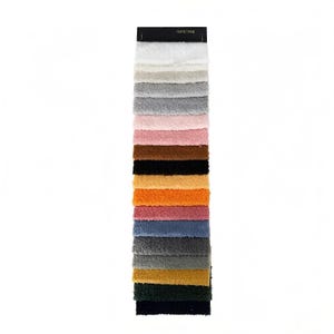 May include: A fabric swatch card featuring a variety of plush, textured samples in a range of colors. The colors include white, beige, gray, pink, brown, black, orange, red, blue, and green. The card is rectangular with a black header.
