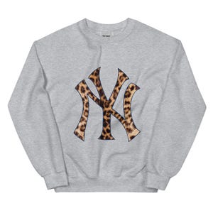 May include: A gray sweatshirt with a large, brown and black leopard print New York Yankees logo.
