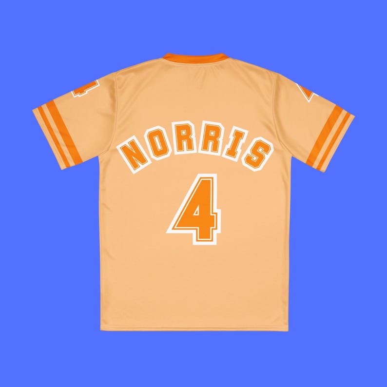 Op de afbeelding: Een lichtoranje honkbalshirt met de naam "NORRIS" in witte blokletters en het nummer "4" in wit. Het shirt heeft oranje strepen op de mouwen en de kraag. De achtergrond is effen blauw.