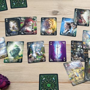 Pode incluir: Um conjunto de cartas de tarot com v&aacute;rias ilustra&ccedil;&otilde;es e texto, incluindo "Queen of Swords", "The Tower" e "Ace of Swords". As cartas est&atilde;o dispostas sobre uma superf&iacute;cie de madeira clara, com algumas rosas roxas secas em primeiro plano.
