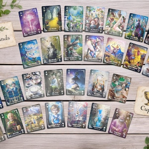 Pode incluir: Um conjunto de cartas de tarot com ilustra&ccedil;&otilde;es de fantasia, dispostas sobre uma superf&iacute;cie de madeira. As cartas exibem v&aacute;rias cenas e personagens, com os naipes de Paus e Copas indicados por cartas separadas. As obras de arte s&atilde;o detalhadas e coloridas.