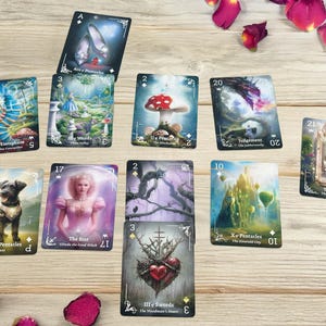 Pode incluir: Um conjunto de cartas de tarot com v&aacute;rias ilustra&ccedil;&otilde;es, incluindo um c&atilde;o, um cogumelo e um castelo. As cartas est&atilde;o dispostas sobre uma superf&iacute;cie de madeira clara, com p&eacute;talas de rosa espalhadas. Cada carta tem um t&iacute;tulo e um n&uacute;mero.