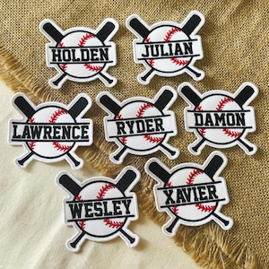 May include: Baseball-themed patches with personalized names. Each patch features a baseball with red stitching, crossed black bats, and a white banner with a name in black. Names include Holden, Julian, Lawrence, Ryder, Damon, Wesley, and Xavier.