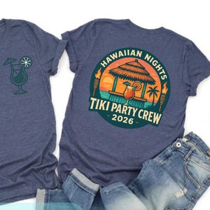 Puede incluir: Dos camisetas azul marino con diseños tropicales. Una camiseta tiene un gráfico de cóctel, la otra tiene un diseño de "Hawaiian Nights Tiki Party Crew 2026". También es visible el texto "ALL TEXTS & THE YEAR SECTION CAN BE CUSTOMIZED".