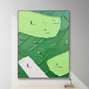 May include: An abstract painting of a golf course with golfers. The artwork features a textured, green and white landscape with miniature figures of golfers in action. The painting is framed in a light brown wooden frame.