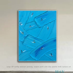 May include: Abstract painting with a textured blue background and small figures surfing on waves. The artwork features a palette knife technique, creating a 3D effect. The painting is framed in white and mounted on a wall.