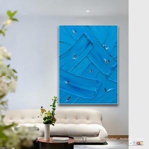 Puede incluir: Una pintura sobre lienzo rectangular de gran tama&ntilde;o con gruesas pinceladas de pintura azul texturizada superpuestas en la superficie. Peque&ntilde;as figuras detalladas de surfistas sobre olas est&aacute;n dispersas por toda la composici&oacute;n.