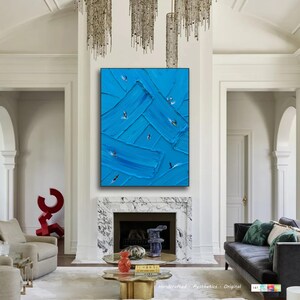 Puede incluir: Una pieza de arte mural rectangular con un fondo azul vibrante y trazos de pintura gruesos y texturizados. Peque&ntilde;as figuras detalladas de surfistas sobre tablas est&aacute;n dispersas por la superficie azul, creando una sensaci&oacute;n de movimiento.