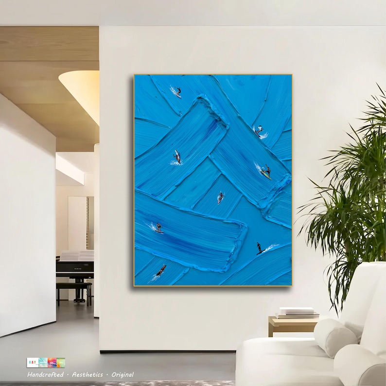 Puede incluir: Una pieza de arte mural rectangular con un fondo azul vibrante y trazos de pintura gruesos y texturizados. Peque&ntilde;as figuras oscuras de surfistas sobre tablas est&aacute;n dispersas por la superficie azul, creando una sensaci&oacute;n de movimiento.