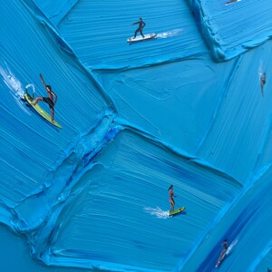 Op de afbeelding: Een olieverfschilderij met dikke, getextureerde blauwe impasto-penseelstreken die oceaangolven voorstellen. Verschillende kleine figuren surfen op kleurrijke planken over het oppervlak, wat een contrast vormt tussen de verf en de figuren.