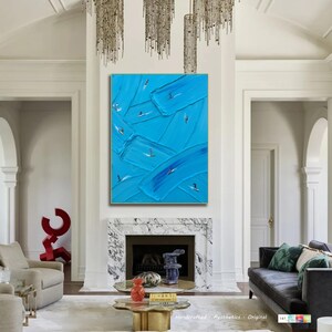 Op de afbeelding: Een groot rechthoekig wandkunstwerk met een levendige blauwe achtergrond en dikke, getextureerde verfstreken. Kleine, gestileerde figuren van mensen op surfplanken zijn verspreid over het doek en lijken op de blauwe golven te surfen.