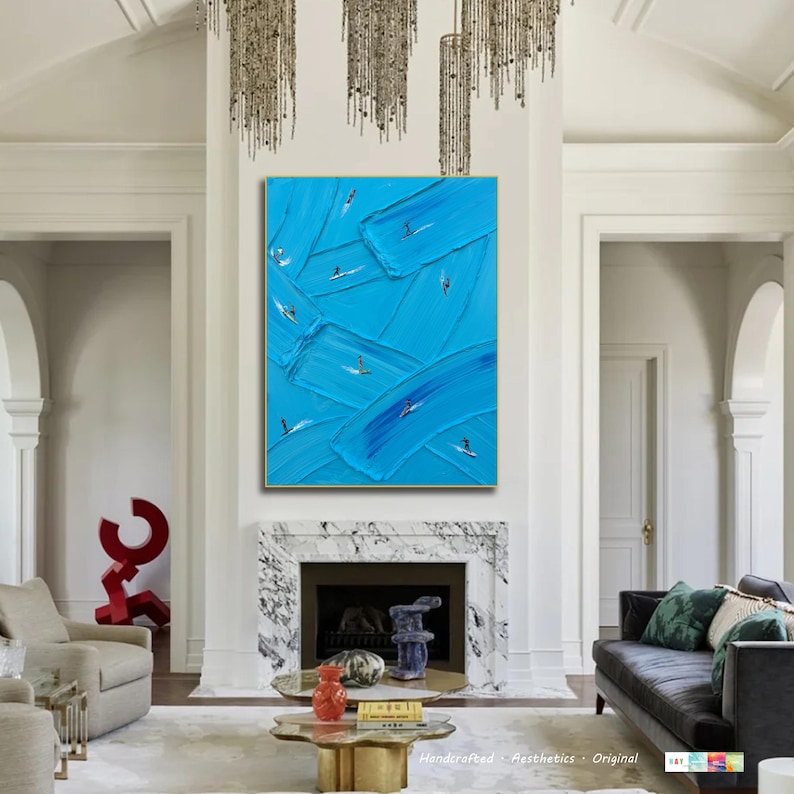 Op de afbeelding: Een groot rechthoekig wandkunstwerk met een levendige blauwe achtergrond en dikke, getextureerde verfstreken. Kleine, gestileerde figuren van mensen op surfplanken zijn verspreid over het doek en lijken op de blauwe golven te surfen.