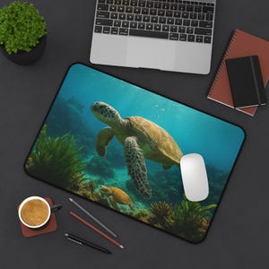 May include: A rectangular mousepad featuring a vibrant underwater scene with two sea turtles swimming near coral and seaweed. The mousepad has a black border and a white computer mouse is on the right side.