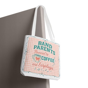 以下が含まれることがあります： ギンガムチェック柄の白いトートバッグ。「BAND PARENTS Powered by COFFEE and Earplugs」の文字入り。リボンと音符が付いたコーヒーカップのグラフィックが特徴です。